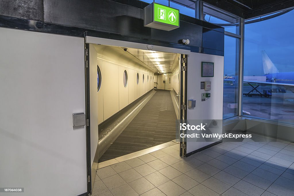 Airport Gate Looking inside an open gate at Schiphol Airport. Outside an airplane is being catered. Cloudy sky at an early morning in Amsterdam. Airplane Stock Photo