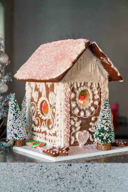 Gingerbread house with white and pink icing. Homemade for Christmas holiday. Portrait vertical view.