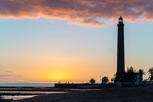 Beautiful sunset view on the beach with lighthouse in Maspalomas city on Gran Canaria island.