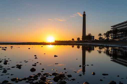 Beautiful sunset view on the beach with lighthouse in Maspalomas city on Gran Canaria island.