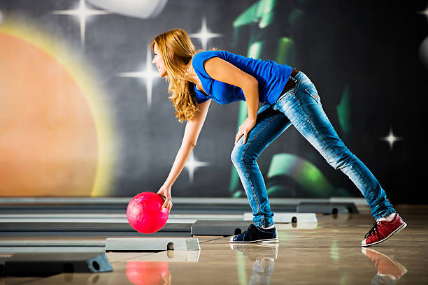 junge frau werfen eine bowlingkugel. - bowling holding bowling ball hobbies stock-fotos und bilder