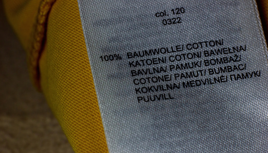 Close up macro shot of a cloth label mentioned of its material as cotton written in various languages