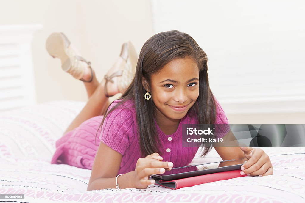 Афро-американских девочка с помощью цифрового планшета на дому в спальне - Стоковые фото Африканская этническая группа роялти-фри