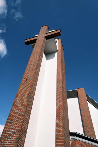 An oversized cross with three stylized nails at the modern steeple of listed Catholic 