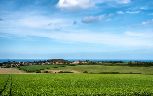 Bright green meadows and agricultural fields extend to coastline of North Sea in Norfolk