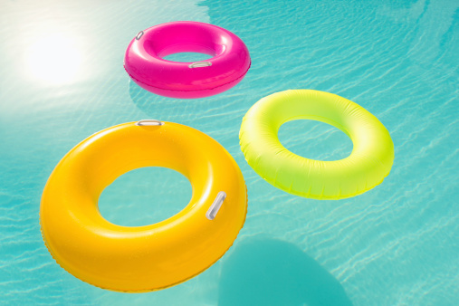 Colorful inflatable rings floating in tourist resort pool.