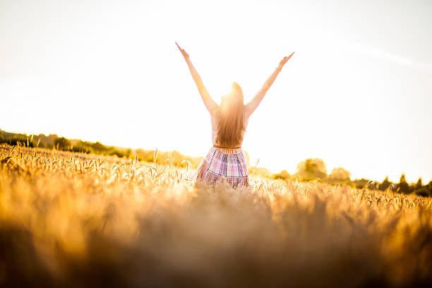Woman In A Wheat Field Raising Hand Towards Sky