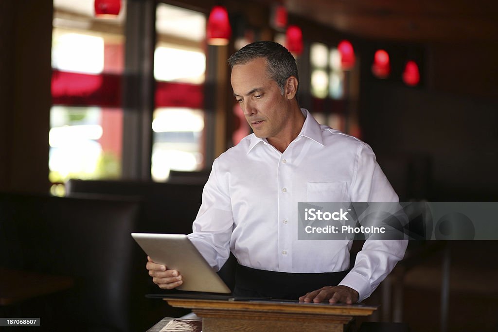 Waiter Reading Order On Digital Tablet Mature waiter reading order on digital tablet at restaurant podiumhttp://i449.photobucket.com/albums/qq220/iphotoinc/MobileBankingLightbox_zps4f4602a2.jpg 40-49 Years Stock Photo