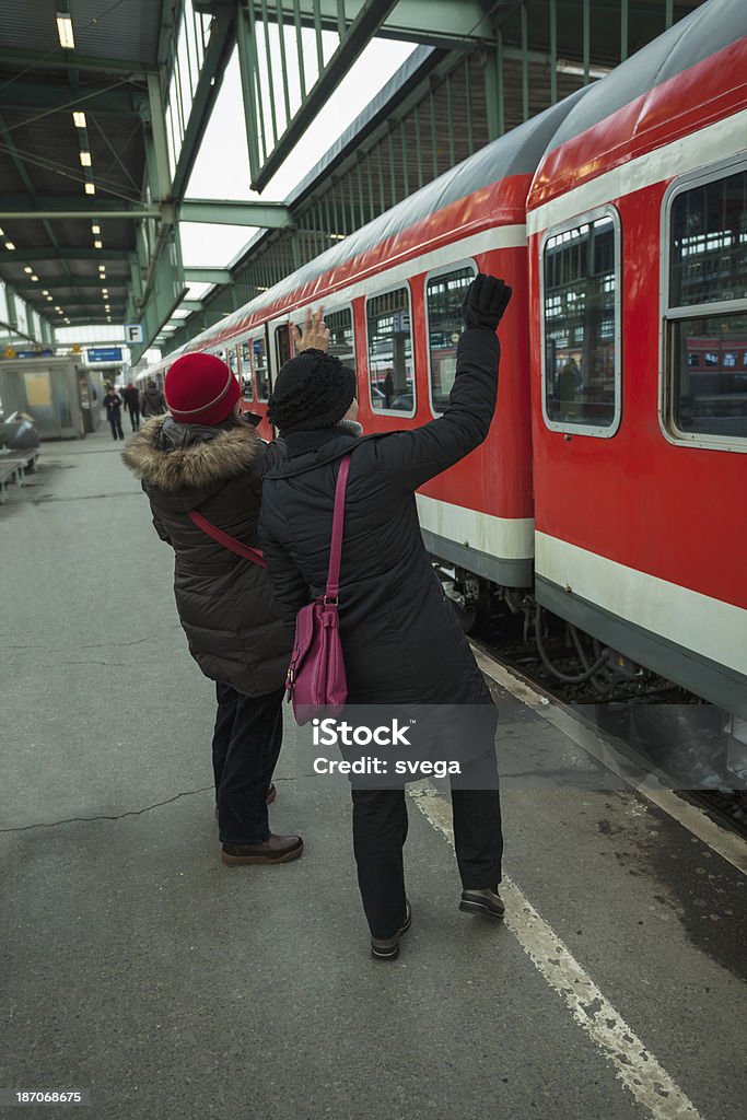 Duas mulheres na estação de trem, acenando para um amigo em trem - Foto de stock de Acenar royalty-free