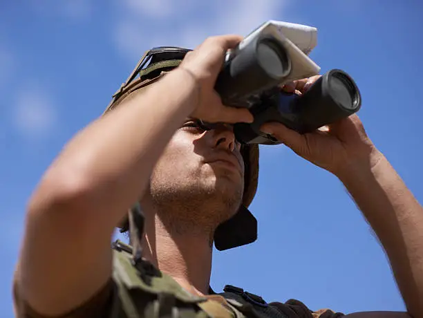 A young soldier looking through his binoculars