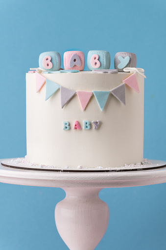 Baby shower party cake with white chocolate frosting. Guess the gender of the upcoming child. He or She cake. Reveal the gender of the unborn baby. Blue or pink sponge bisquit inside. Blue background