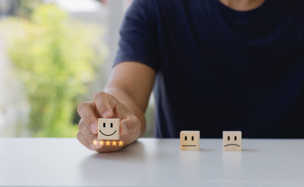istock Customer services best excellent business rating experience. Client satisfaction feedback survey concept. Hand of a business person chooses a smiley face on a wooden cube block. 5 Star Satisfaction. 1870703518