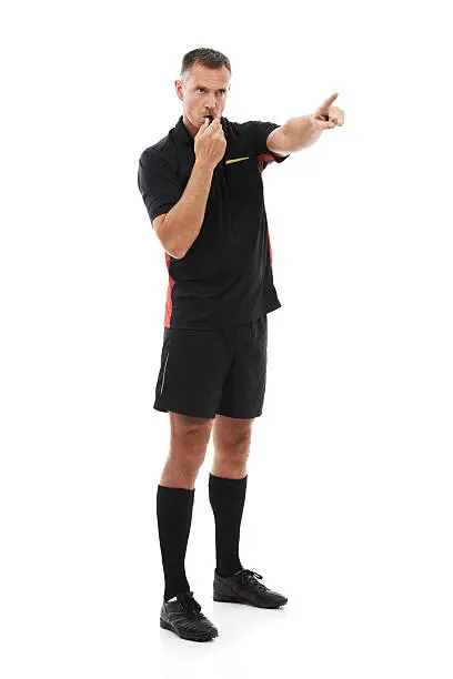 A referee blowing his whistle and pointing isolated against a white background