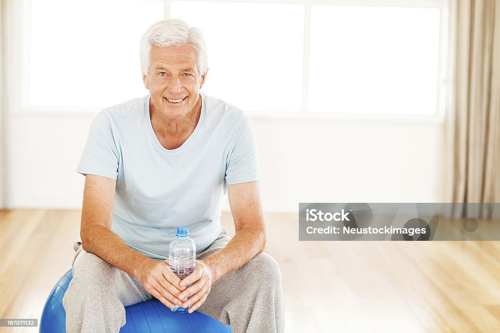Uomo anziano seduto su Palla Fitness - Foto stock royalty-free di 60-69 anni