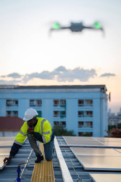 istock Technician working on ecological solar farm. Renewable clean energy technology concept. Specialist engineer control drone checking top view of installing solar roof panel on the factory rooftop 1870712450