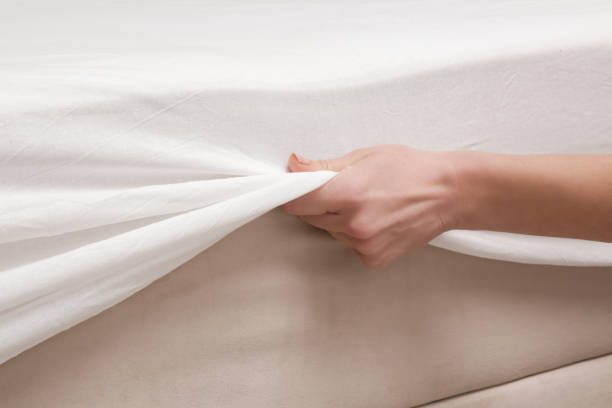 istock Changing bed sheets. Woman is putting on a fitted white cotton sheet on a mattress while making the bed. 1870714327