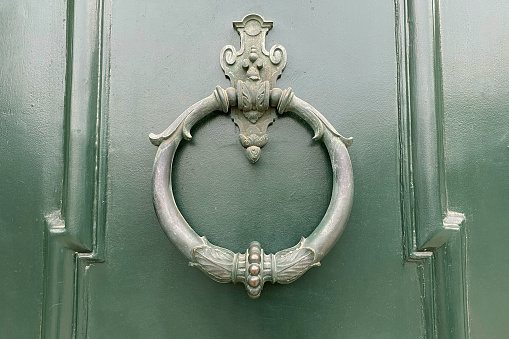 Old door knocker in the form of a circle on a green door