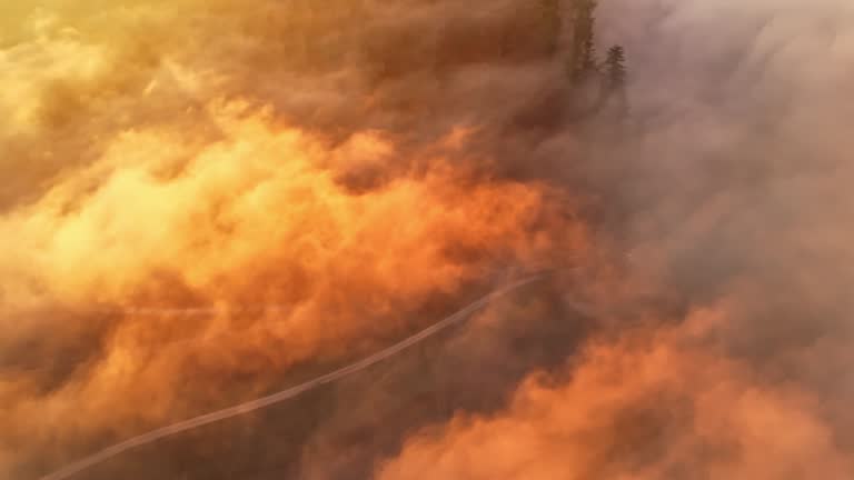 AERIAL Drone Spinning Above Sunlit Clouds over Winding Road Amidst Agricultural Fields at Sunrise