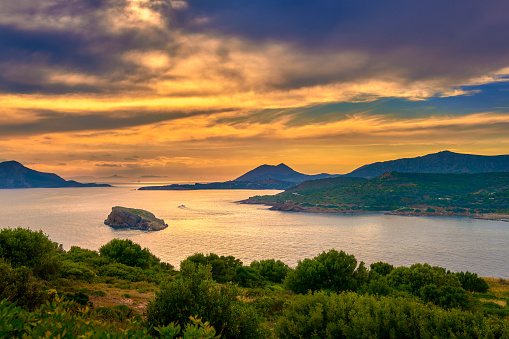 Sunset on Mediterranean sea coast, summer evening at ancient Temple of Poseidon, Sounio, Greece. Tranquil coastal landscape with clear blue waters.