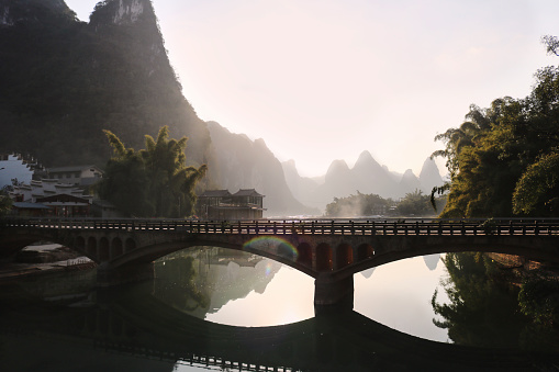 Dreamy Bridge over the Li River in Yangshuo, Guangxi, China with mountain scenery in the background and sun flare, no people