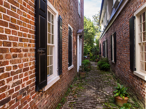 Narrow brick path between two red, historic brick houses in Savannah, Georgia.