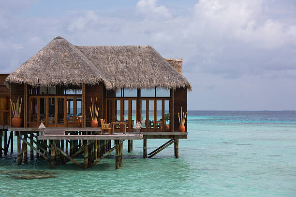Boardwalk connecting seashore and small beach hut at sea.