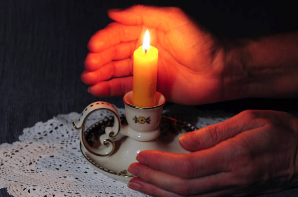 istock a lit candle between women's palms in the dark silence and condolences, light 1870768096