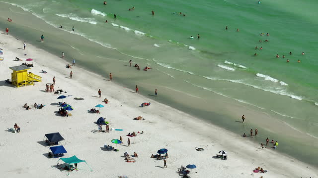 Aerial view of Siesta Key beach in Sarasota, USA. Many people enjoing vacation time swimming in gulf water and relaxing on warm Florida sun