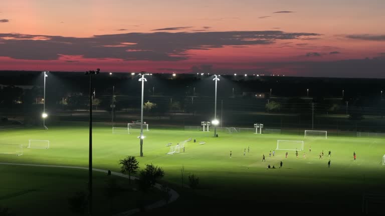 People playing soccer game on illuminated public stadium at night. Active way of life concept