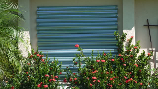 Boarded up windows with steel storm shutters for hurricane protection of residential house. Protective measures before natural disaster in Florida