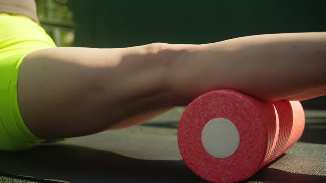 Young woman does self massage with pink MFR roller close-up. Massage roller for myofascial release. Health. Stretching outdoor