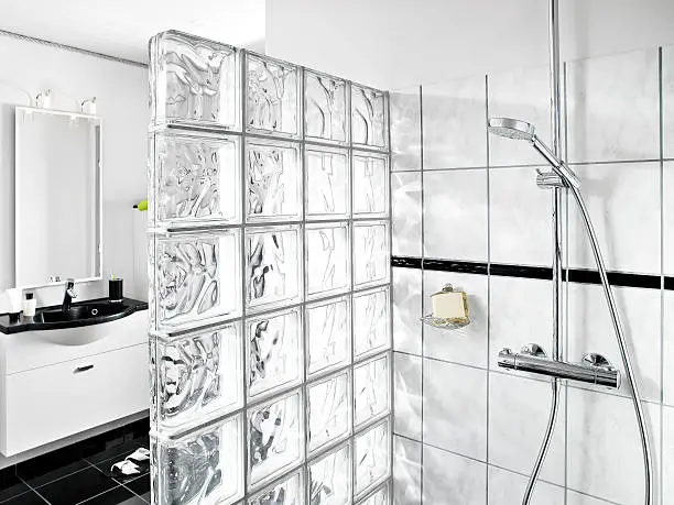 White designer bathroom with glass brick shower corner and black shiny granite floor