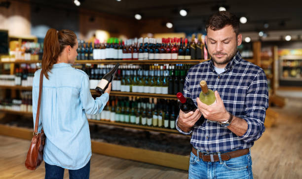 ludzie konsumenci wybierający wino w sklepie monopolowym. - wine bottle liquor store wine variation zdjęcia i obrazy z banku zdjęć