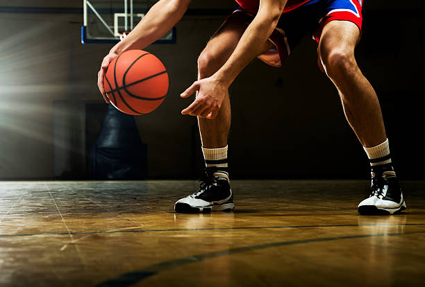 Unrecognizable basketball player dribbling. Basketball player is dribbling on the basketball court.    running shoes on floor stock pictures, royalty-free photos & images