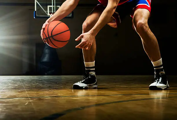 Basketball player is dribbling on the basketball court.   