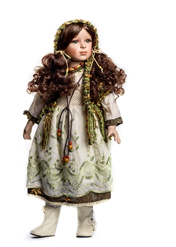 Modern doll with brown curly hair in a beautiful dress isolated on a white background. Close-up portrait.
