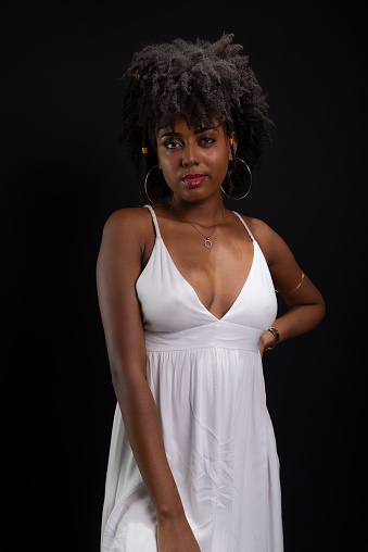 Portrait of a beautiful woman, looking at the camera, with black hair, wearing white clothes. Isolated on black background.