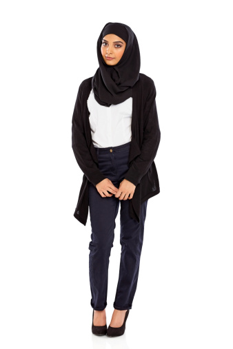 Portrait of a young Muslim woman in a head scarf standing over white background