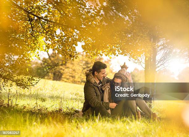 Happy Couple Under Tree In The Autumn Park Stock Photo - Download Image Now - Adult, Adults Only, Autumn