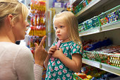 Girl Having Arguement With Mother At Candy Counter In Supermarket