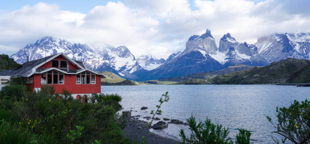 A tranquil sunset at Lake Azul in Torres del Paine, Patagonia, with weathered wooden posts leading to serene waters framed by majestic mountain peaks.