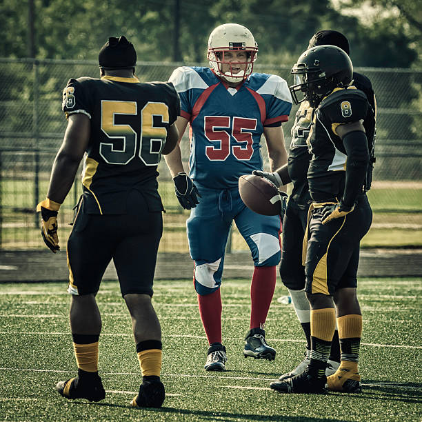 American football team celebrating victory lifting coach on shoulders on field at night