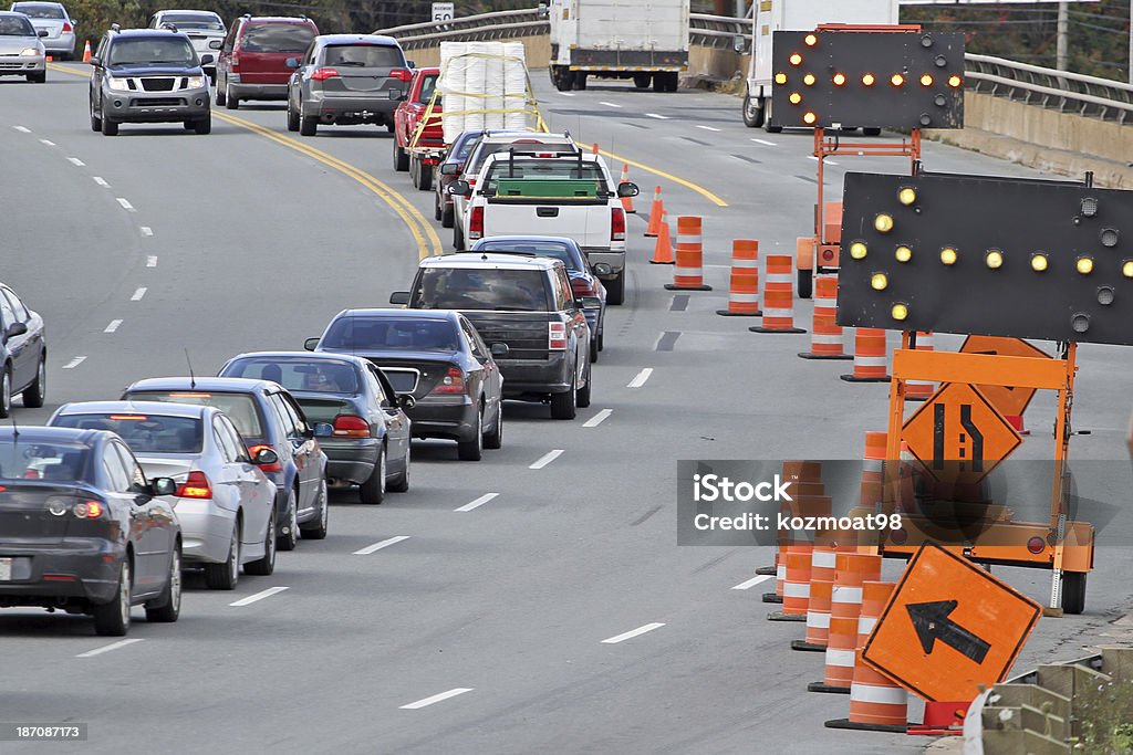 Traffic Control Standard road signs, digital flashing arrows  and traffic cones direct all traffic into the left lane on a road construction site. Road Construction Stock Photo