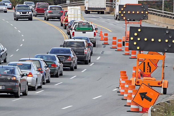 Traffic Control Standard road signs, digital flashing arrows  and traffic cones direct all traffic into the left lane on a road construction site. traffic cone photos stock pictures, royalty-free photos & images