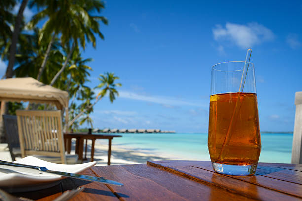 Ice Tea On Table A cup of  ice tea  on outdoor table with beach background holiday camp stock pictures, royalty-free photos & images