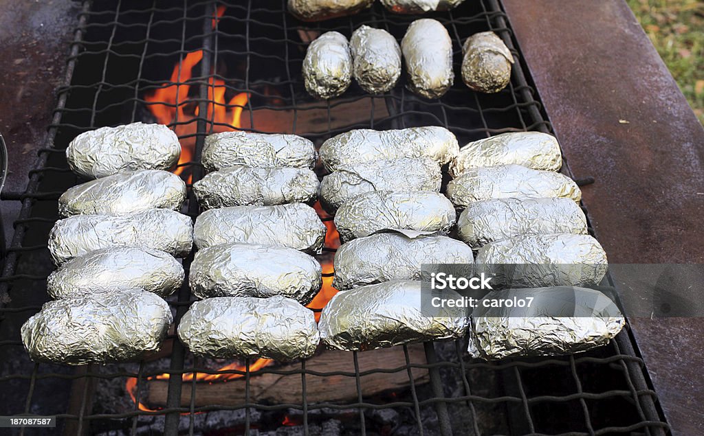Foil envolto batatas assadas de culinária no fogo aberto.  Chamas. - Foto de stock de Batatas Prontas royalty-free
