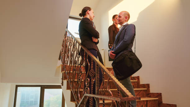 istock Business partners standing on busy staircase talking 1870884598
