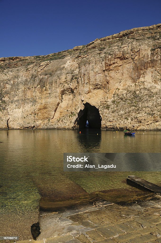 Dweijra, Gozo, Malta. The inland sea connected the natural tunnel you can just see daylight at the other end used by fishermen for centuries in Winter weather. Blue Stock Photo