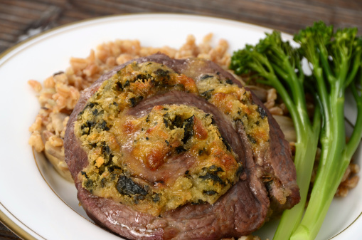 Flank steak stuffed with spinach, cheese and breadcrumbs and rolled into a pinwheel, served with broccolini and farro.