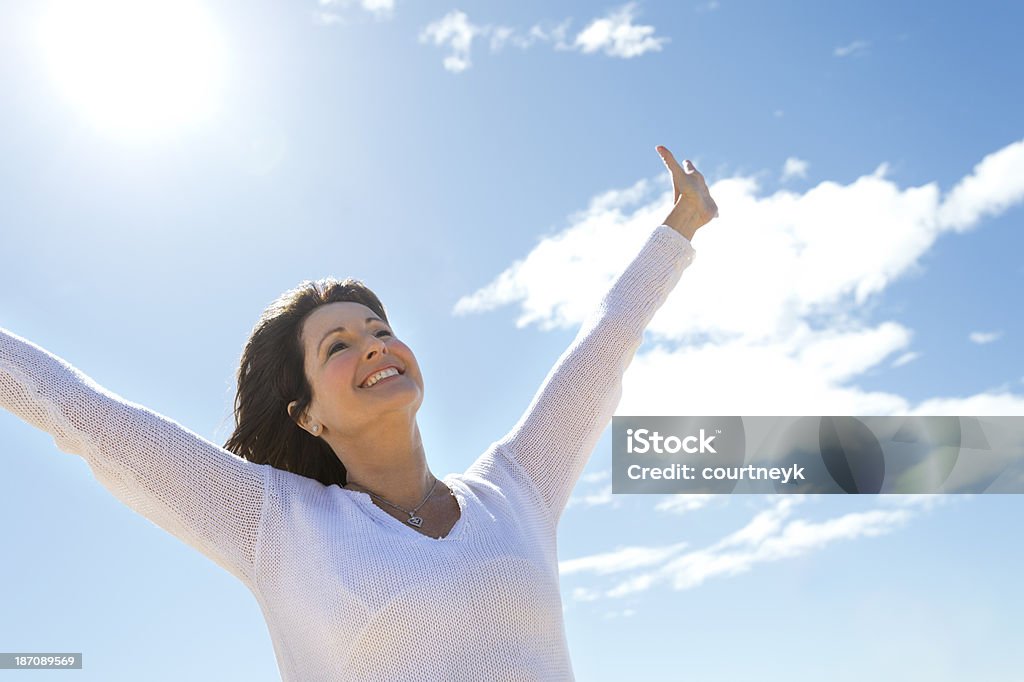 joyful mature woman smiling with arms up in a V shape Joyful mature woman smiling outdoors Mature Women Stock Photo